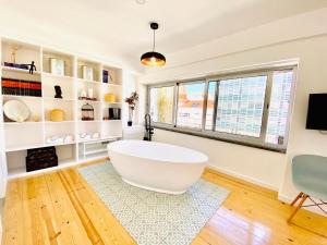 una gran bañera blanca en una habitación con ventanas en The Postcard Avenue, en Lisboa