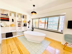 a large white bath tub in a room with windows at The Postcard Avenue in Lisbon +48 photos