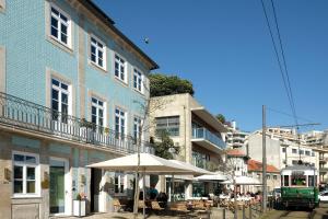 un bâtiment bleu avec un parasol dans une rue de la ville dans l'établissement Vila na Praia Foz Luxury Apartments, à Porto