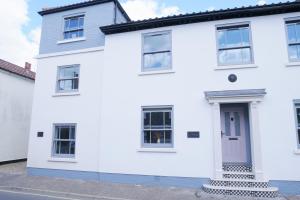 a white house with a blue door at New street Luxury town house in the centre of Holt with free PARKING for one car in Holt