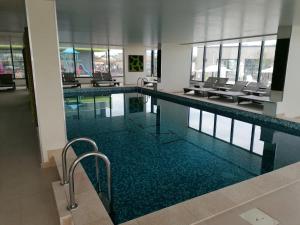 ein großer Pool in einem Gebäude mit Stühlen in der Unterkunft GreenView Alezzi Beach Resort in Mamaia Nord – Năvodari