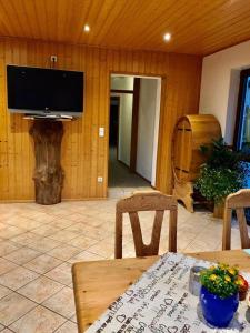 een woonkamer met een tv en een tafel en stoelen bij Waldnest Odenwald in Wald-Michelbach