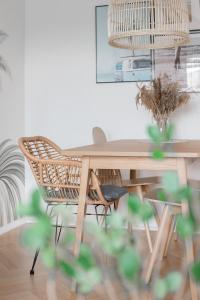 a dining room table with a rattan chair at Home3city Green 300 m do morza in Sopot