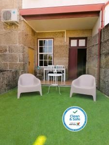 a patio with two white chairs and a table at 4-As center apartments in Guimarães