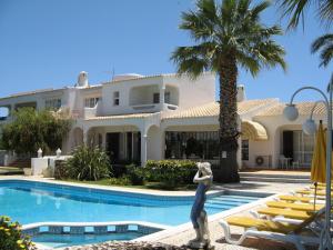 une grande maison blanche avec une piscine et des palmiers dans l'établissement Quinta dos Oliveiras, à Carvoeiro