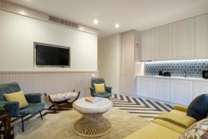 Vila na Praia Foz Luxury Apartments في بورتو: غرفة معيشة مع أريكة وكراسي وتلفزيون