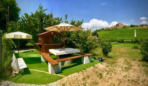 a picnic table with an umbrella on the grass at Wellness Suite Na' Canuna' in Roddi