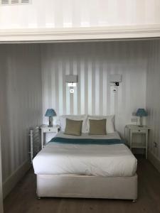 a bedroom with a large white bed with two tables at Elsham Apartments in London