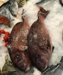 two fish on a plate with rice and tomatoes at Esmeralda Hotel & Restaurant in Ksamil