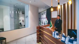 a man standing behind a counter in a lobby at Iridium Hotel in Taif