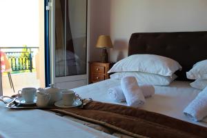 a bed with two cups and towels and a tray with two mugs and two at Sofia Apartments in Koroni