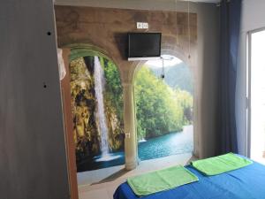 ein Schlafzimmer mit einem Gemälde eines Wasserfalls in der Unterkunft Hostal Sant Jordi in Tossa de Mar
