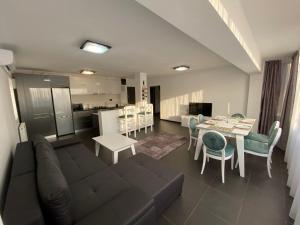 a living room with a couch and a table and a kitchen at Cara Apartment - 5 min walk to the beach (Delfinariu - bd. Mamaia) in Constanţa