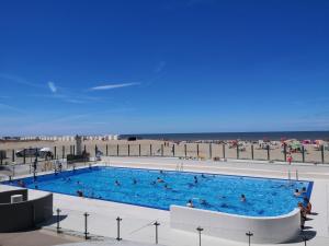 a large swimming pool next to a beach at Zeester en koffie. in Oostduinkerke-Bad