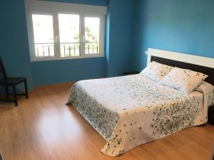 um quarto azul com uma cama e 2 janelas em El Capricho em Cue