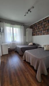 two beds in a room with wooden floors and windows at Pensión Bide-Ondo in Amorebieta-Etxano