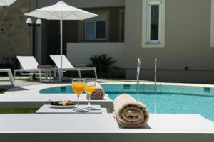 a table with two glasses of wine next to a pool at Limosa Luxury Residences in Kissamos