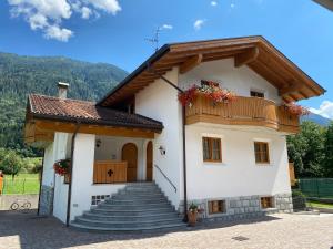 a small white house with a balcony and stairs at Villa Golf in Pinzolo