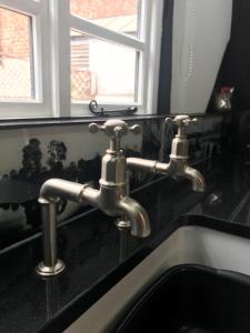 a bathroom sink with two faucets on a black counter at "Wesley House" Historic home in town Centre with Parking in Shrewsbury