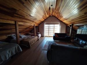een kamer met een houten plafond, een bed en een bank bij Chalé aconchegante próximo ao aeroporto in São José dos Pinhais