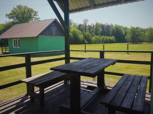 una mesa de picnic de madera en un porche con un granero en Ignatówka, en Darłowo