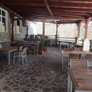 een restaurant met houten tafels en stoelen en een bakstenen muur bij Vila Briana in Păltiniş