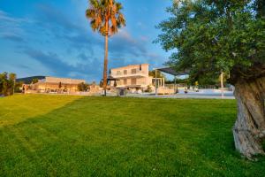a green yard with a palm tree and a building at Dardiza Boutique Hotel in Ermioni
