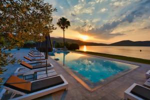 a pool with lounge chairs next to a body of water at Dardiza Boutique Hotel in Ermioni