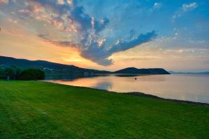 a sunset over a body of water with a green field at Dardiza Boutique Hotel in Ermioni