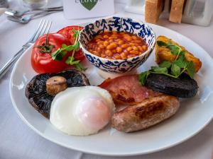 a plate of food with eggs sausage beans and tomatoes at Cloves Boutique Bed & Breakfast in Cleethorpes