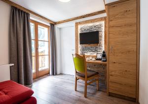 a room with a desk with a chair and a television at AlpinSpa zur Post - Bergbahn im Sommer 2025 inklusive in Bad Gastein
