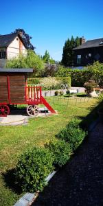 un train rouge sur une aire de jeux dans une cour dans l'établissement La Cour Du Puits chambre Maxime, à Cormeilles