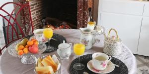 - une table avec petit-déjeuner composé de fruits et de jus d'orange dans l'établissement La Cour Du Puits chambre Maxime, à Cormeilles