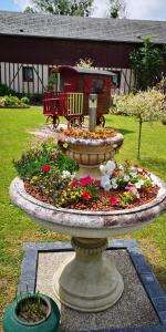 una fuente con un tren en un jardín con flores en La Cour Du Puits chambre Maxime, en Cormeilles