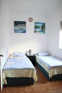 een slaapkamer met 2 bedden en een klok aan de muur bij Sobe-Apartmani Modriča in Modriča