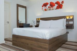 a bedroom with a large bed and a mirror at Langley Guest House in Slough