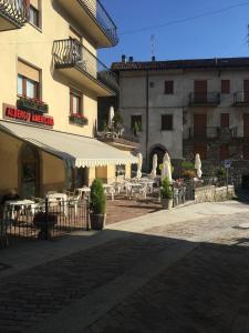 a patio with tables and chairs in front of a building at Hotel Americana in Serina