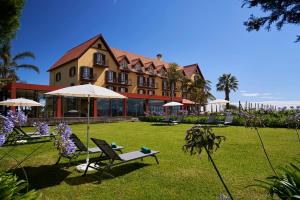 a large building with chairs and umbrellas in a yard at Hotel Quinta Do Furao in Santana