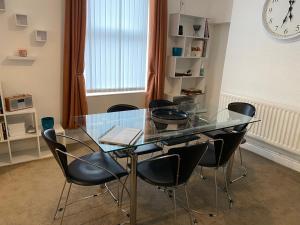 a glass table and chairs in a room with a clock at 39 Cowley Road in Liverpool +22 photos