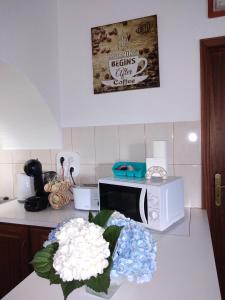 a kitchen with a microwave and flowers on a counter at Casa dos Valentes in Santo Espírito
