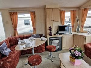 a living room with a couch and a table at Private Caravan on Palins Holiday Park, North Wales in Foryd