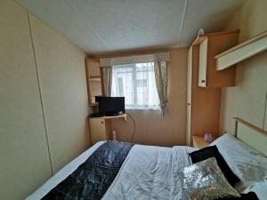 a small bedroom with a bed and a window at Private Caravan on Palins Holiday Park, North Wales in Foryd +35 photos