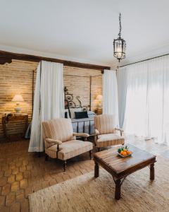 een woonkamer met 2 stoelen en een tafel en een bed bij Finca Monasterio in San Martín del tesorillo