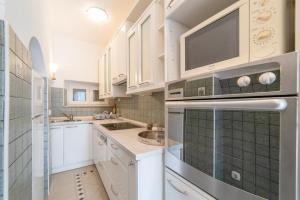Una cocina con gabinetes blancos, un fregadero y un microondas. en Apartman Anđelina Old Town Cavtat, en Cavtat