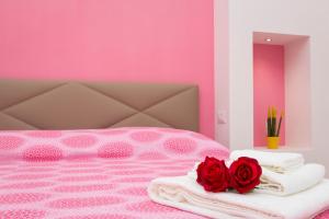 聖安吉洛的住宿－Casa vacanze Le tre rose，粉红色的卧室,配有带毛巾和玫瑰的床