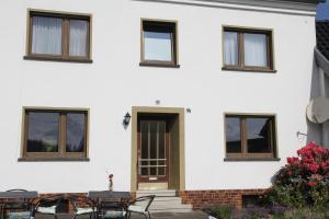 ein weißes Haus mit Tischen und Fenstern in der Unterkunft Bike and Hike Ferienhaus Kolverath in Kolverath