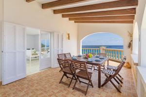 uma sala de jantar com uma mesa e vista para o oceano em Villa Torre Vea em Punta Prima