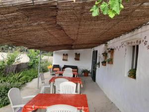 a patio with tables and chairs under a wooden roof at Es Barranco in Ferreries
