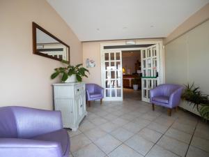 Hotel La Rosa Dei Venti في ألبينيا: غرفة معيشة مع كراسي أرجوانية ومرآة