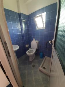 Baño de azulejos azules con aseo y lavamanos en Hillside Apartments, en Borsh